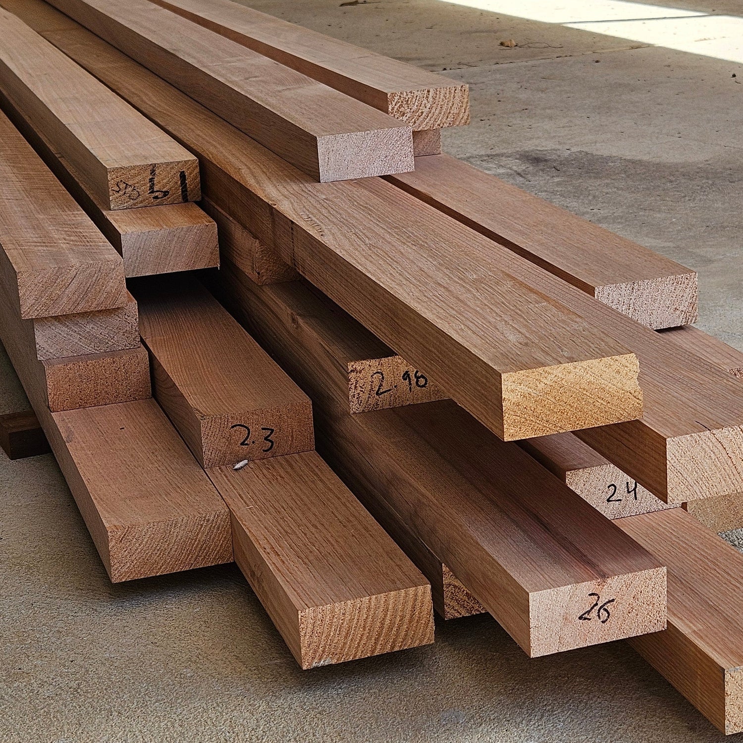 Stack of wooden planks with measurements on a concrete floor